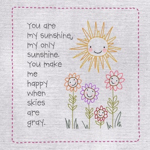 May include: Embroidered artwork with the text "You are my sunshine, my only sunshine. You make me happy when skies are gray." Features a smiling sun and colourful flowers with smiling faces. The artwork is framed with a pink dotted border.