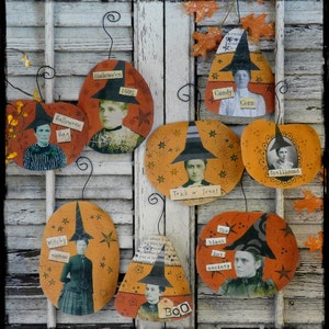 May include: A collection of eight handmade Halloween-themed pumpkin ornaments. Each pumpkin is decorated with a witch wearing a black hat and a different Halloween-themed phrase. The phrases include "Halloween Hag", "Halloween 1692", "Candy Corn", "Spellbound", "Trick or Treat", "Witchy Woman", "The Black Hat Society", and "BOO".