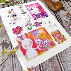 May include: A sheet of paper featuring colourful illustrations of bunnies and flowers. The illustrations are in a whimsical style with bright colours and bold lines. The paper is white with a textured surface.