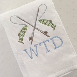 May include: White cloth burp cloth with embroidered fishing rods, two fish, and the monogram WTD.