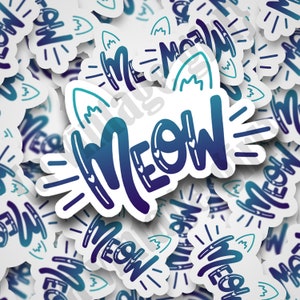 May include: A collection of white stickers with a gradient blue and purple "MEOW" design. The word "MEOW" is stylized with cat ears and hearts. The stickers have a white border and are scattered across a white surface.