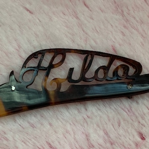 May include: A brown tortoiseshell hair comb with the name "Lida" carved into it.