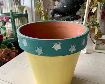 Maceta vintage de terracota pintada en amarillo con estrellas blancas sobre turquesa