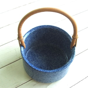 May include: A blue ceramic planter with a brown leather handle. The planter has a speckled blue glaze and is perfect for displaying small plants or flowers.