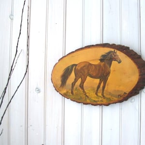 May include: A brown horse with a white mane and tail is painted on a wooden plaque. The plaque is shaped like a tree trunk and has a rough, natural texture.