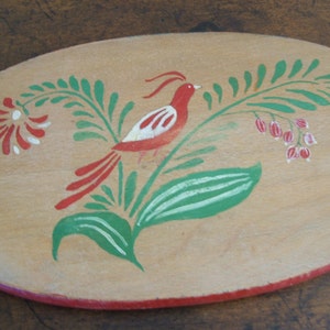May include: A wooden oval-shaped serving tray with a hand-painted design of a red bird with white accents perched on a green leafy branch with red and white flowers.