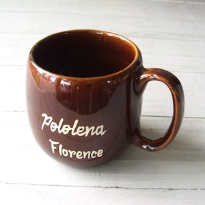 May include: A brown ceramic mug with a white inscription that reads "Pololena Florence".