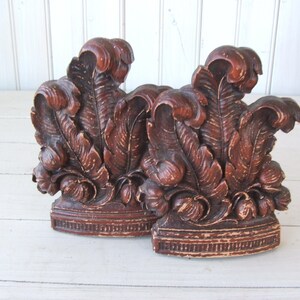 May include: A pair of brown wooden bookends with a carved leaf design. The bookends are distressed and have a rustic look.