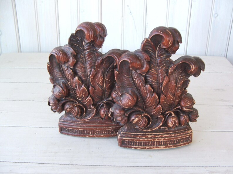 May include: A pair of brown wooden bookends with a carved leaf design. The bookends are distressed and have a rustic look.