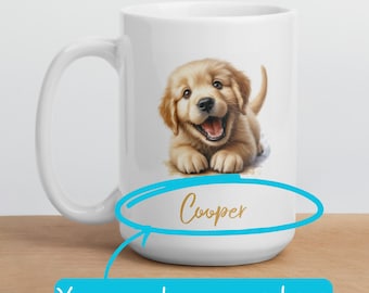 May include: White ceramic mug with a golden retriever puppy illustration. The puppy is smiling and has a brown nose. The text "Cooper" is written in gold below the puppy. The mug is on a wooden surface.