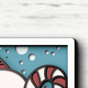 May include: A layered paper art piece featuring a stylized red and white candy cane swirl and a partial red shape with white teeth against a light blue background with circular cutouts. The design uses stacked paper layers to create depth.