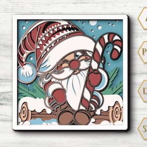 May include: A multi-layered square wall art piece featuring a gnome wearing a red and white hat, holding a red and white candy cane, sitting on a log covered in snow against a light blue background with snowflakes. The text AI, PDF, DXF, and SVG appear in hexagons.
