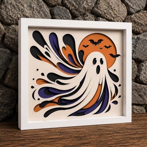 May include: A square white-framed layered paper art piece featuring a central white ghost with a surprised expression, set against a background of orange, purple, and black swirling shapes, with a large orange moon and several black bats silhouettes.