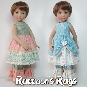 May include: Two dolls wearing layered dresses with ruffled pants. The doll on the left is wearing a green, pink, and blue dress with a green, pink, and white ruffled pant. The doll on the right is wearing a blue, white, and pink dress with a white and pink ruffled pant. The dolls are both wearing brown wigs. The text "Raccoon's Rags" is at the bottom of the image.