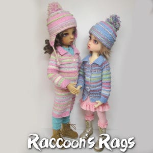 Könnte beinhalten: Zwei Puppen tragen gestreifte Strickjacken und Hüte. Die Puppe links trägt eine rosa und grüne Strickjacke und einen rosa Hut mit einem weißen Bommel. Die Puppe rechts trägt eine blaue und rosa Strickjacke und einen blauen Hut mit einem weißen Bommel. Beide Puppen tragen eine rosa Hose und haben langes braunes Haar.