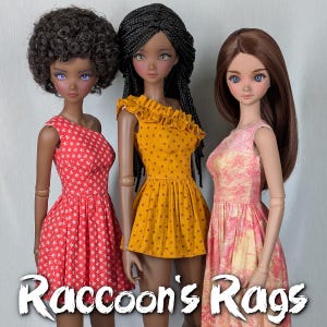 Op de afbeelding: Drie modepoppen in kleurrijke jurken. De pop links draagt een rode jurk met witte sterpatronen. De middelste pop draagt een gele jurk met kleine rode stippen. De pop rechts draagt een roze jurk met bloemenpatroon. De tekst "Raccoon's Rags" staat onderaan.