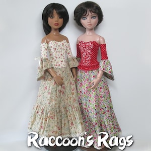 May include: Two dolls wearing floral print dresses with off-the-shoulder tops. The doll on the left is wearing a cream dress with a red floral print. The doll on the right is wearing a green dress with a red and pink floral print. The text "Raccoon's Rags" is visible at the bottom of the image.