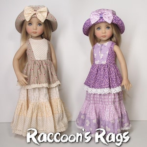 May include: Two dolls wearing matching dresses and hats. The doll on the left is wearing a beige dress with a floral pattern and a beige hat with a bow. The doll on the right is wearing a purple dress with a floral pattern and a purple hat with a bow. Both dolls have long blonde hair. The text "Raccoon's Rags" is at the bottom of the image.