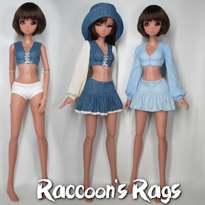May include: Three dolls wearing different outfits. The doll on the left is wearing a white crop top with a lace-up front, white underwear, and a denim skirt. The doll in the middle is wearing a white long-sleeved shirt with a denim crop top, a denim skirt with lace trim, and a blue denim hat. The doll on the right is wearing a light blue crop top with a lace-up front, a light blue skirt, and a long-sleeved light blue shirt. The dolls are all standing on a white background. The text "Raccoon's Rags" is at the bottom of the image.