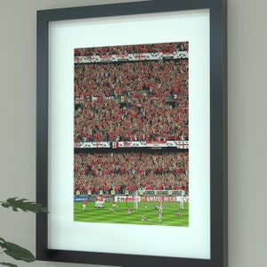 May include: A framed photograph of a football match with a crowd of fans cheering in the background. The players are in the foreground, celebrating a goal. The image includes the text "AMSTEL BEER" and "NUTELLA".