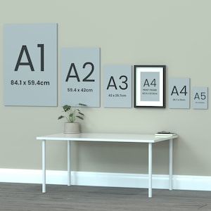 May include: A wall with five different sizes of paper and a print frame. The paper sizes are labeled A1, A2, A3, A4, and A5. The measurements of each size are listed below the label. The print frame is labeled A4 and has the dimensions 42.5 x 32.5 cm. A white table with a plant on it is in the foreground.