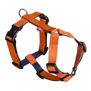Puede incluir: Arnés para perros naranja y azul marino con hebillas de plástico negro y un anillo metálico para sujetar la correa. El arnés está hecho de correas de nailon duraderas y tiene correas ajustables.