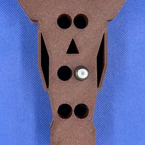 May include: A brown wooden horse head shaped organizer with five holes for storing items. The holes are in the shape of eyes, a nose, and two nostrils.