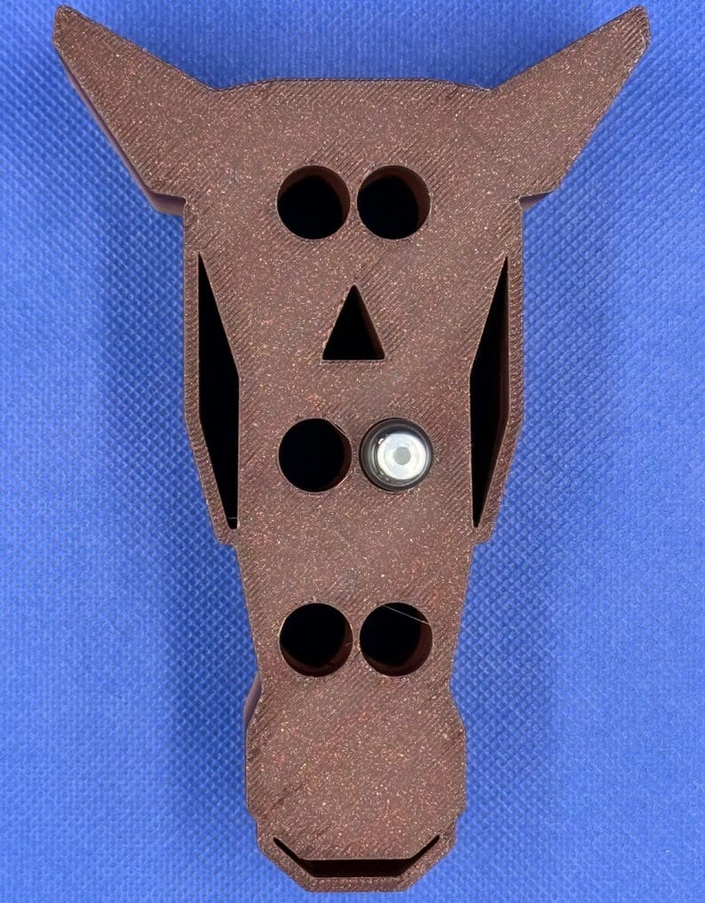 May include: A brown wooden horse head shaped organizer with five holes for storing items. The holes are in the shape of eyes, a nose, and two nostrils.