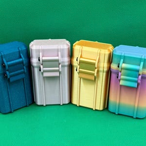 Puede incluir: Cuatro cajas de almacenamiento rectangulares con tapas abatibles y cierres frontales. Las cajas son de color azul oscuro con acabado moteado, rosa claro, amarillo s&oacute;lido y un degradado multicolor que va del morado al amarillo y al azul.