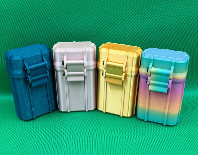 Puede incluir: Cuatro cajas de almacenamiento rectangulares con tapas abatibles y cierres frontales. Las cajas son de color azul oscuro con acabado moteado, rosa claro, amarillo s&oacute;lido y un degradado multicolor que va del morado al amarillo y al azul.