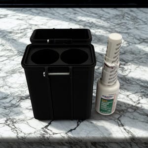 May include: A black rectangular storage container with two circular interior compartments and a metal hinge pin, positioned next to a white plastic bottle of Equate Nasal Mist with a tamper-evident seal around the cap and neck.