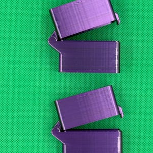 May include: Three purple 3D printed boxes with hinged lids. The boxes are stacked on top of each other.