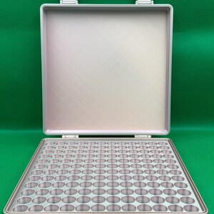 Puede incluir: Un estuche de almacenamiento rectangular de color plateado con tapa abatible, que cuenta con una bandeja interior cuadriculada con numerosos compartimentos circulares para organizar objetos peque&ntilde;os. El estuche tiene dos cierres seguros.