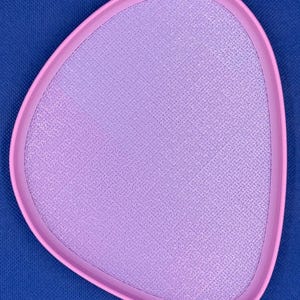 May include: A light pink, oval-shaped tray with a textured surface. The tray has a slightly raised edge.
