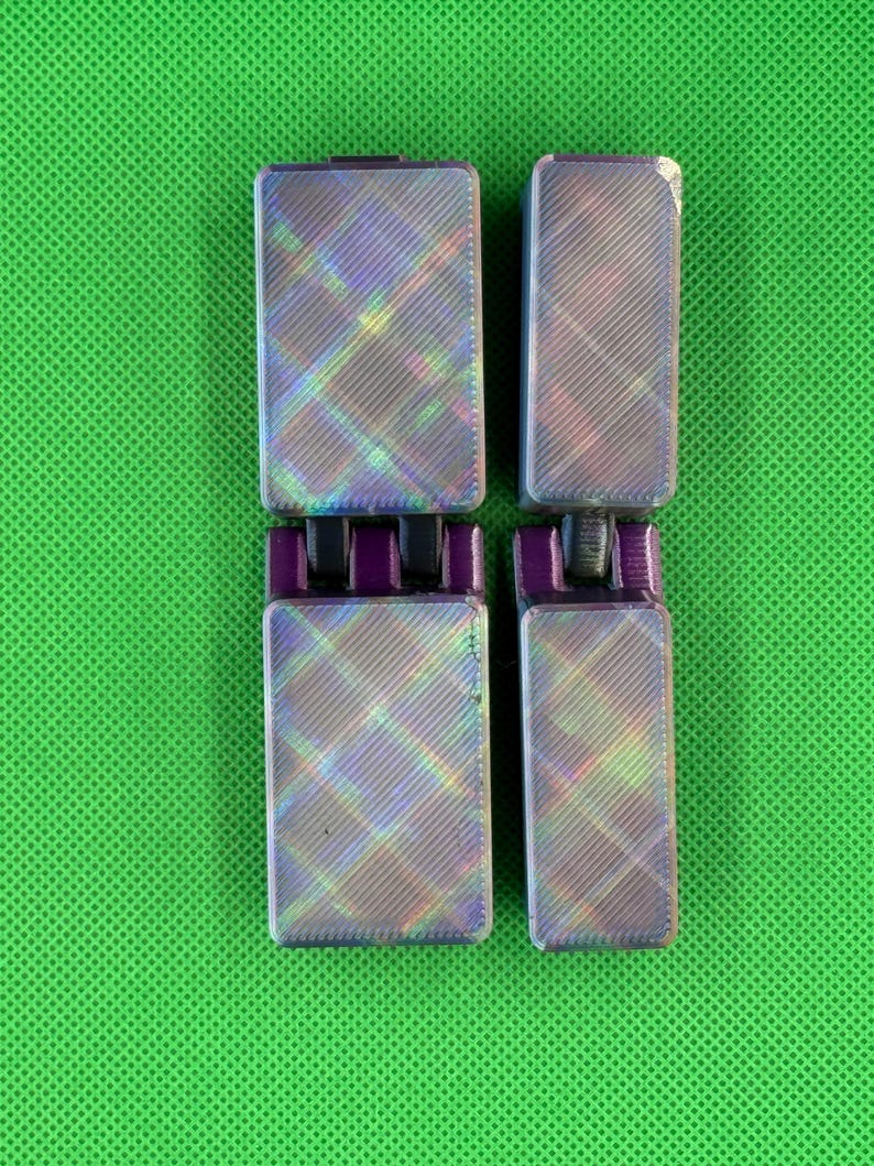 May include: Four iridescent purple and grey rectangular blocks with a chequered pattern. The blocks are arranged in two pairs, stacked on top of each other.