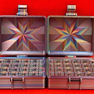 May include: A multi-colored metal storage box with a starburst design on the lid. The box has 24 compartments for storing small items.