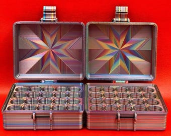 May include: Two rectangular storage cases with hinged lids, featuring a multi-colored iridescent finish. The interior of each lid displays a geometric starburst pattern, while the base contains a grid of twenty circular compartments.