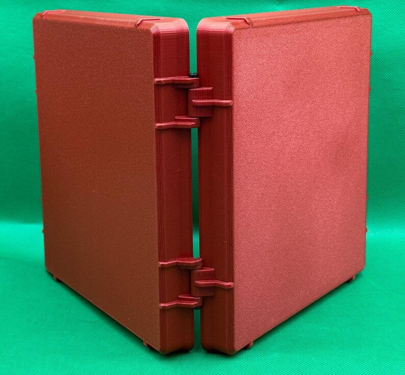 May include: A red, hinged, plastic storage box with a textured surface. The box is closed and the two halves are facing each other.