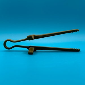 May include: A dark olive green kitchen tong featuring a single-piece molded design with a circular handle loop, two integrated support rests on the exterior of the arms, and serrated gripping edges at the tips for secure handling of food items.