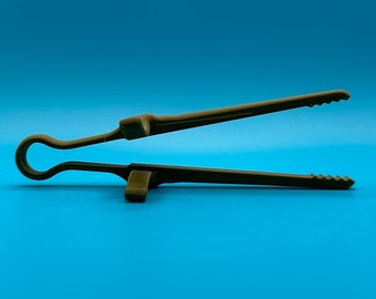 May include: A dark olive green kitchen tong featuring a single-piece molded design with a circular handle loop, two integrated support rests on the exterior of the arms, and serrated gripping edges at the tips for secure handling of food items.