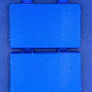 K&ouml;nnte beinhalten: Ein rechteckiger Aufbewahrungskoffer aus blauem Kunststoff mit strukturierter Oberfl&auml;che, bestehend aus zwei klappbaren Abschnitten, die durch ein Mittelgelenk verbunden sind, und zwei blauen Schnappverschl&uuml;ssen.