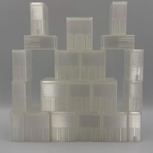 May include: A collection of translucent, rectangular plastic storage containers stacked in a pyramid formation. Each container features a ribbed, vertical texture on the exterior surface and a clear, semi-transparent finish throughout the structure.