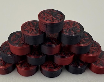 May include: A pyramid arrangement of small, cylindrical containers. Each container features a black and red marbled lid with a textured, swirling pattern. The sides of the containers are solid black or red, showing a layered, ribbed construction.