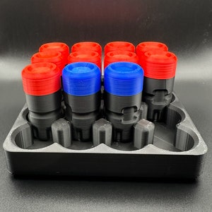 May include: A black 3D-printed storage tray holding twelve cylindrical components. Each component features a black base and a colored top cap, with ten red caps and two blue caps arranged in a grid. The tray has molded slots for each unit.