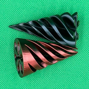 May include: Two conical objects with a spiral, ribbed design. One object is solid black, and the other is a metallic copper color with a dark interior. Both items feature a pointed tip and a wide, circular base with a six-petaled floral cutout pattern.