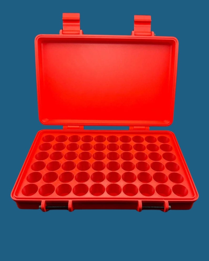 K&ouml;nnte beinhalten: Ein leuchtend roter, rechteckiger Aufbewahrungskoffer mit Klappdeckel und zwei Schnappverschl&uuml;ssen. Der Innenboden verf&uuml;gt &uuml;ber ein Raster aus sechsundf&uuml;nfzig kreisf&ouml;rmigen, vertieften F&auml;chern, die in acht Reihen zu je sieben angeordnet sind.