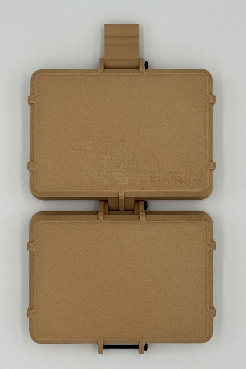 Puede incluir: Una funda con bisagras de color marr&oacute;n claro con forma rectangular. La funda est&aacute; dividida en dos secciones, conectadas por una bisagra en la parte superior. Cada secci&oacute;n tiene una forma rectangular con esquinas redondeadas y una superficie texturizada. La funda tiene un pestillo en la parte inferior.