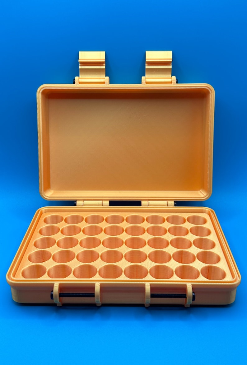 May include: A rectangular, light orange storage case with an open lid and two top hinges. The interior base features a grid of forty circular compartments arranged in five rows of eight, designed for holding small cylindrical items securely.
