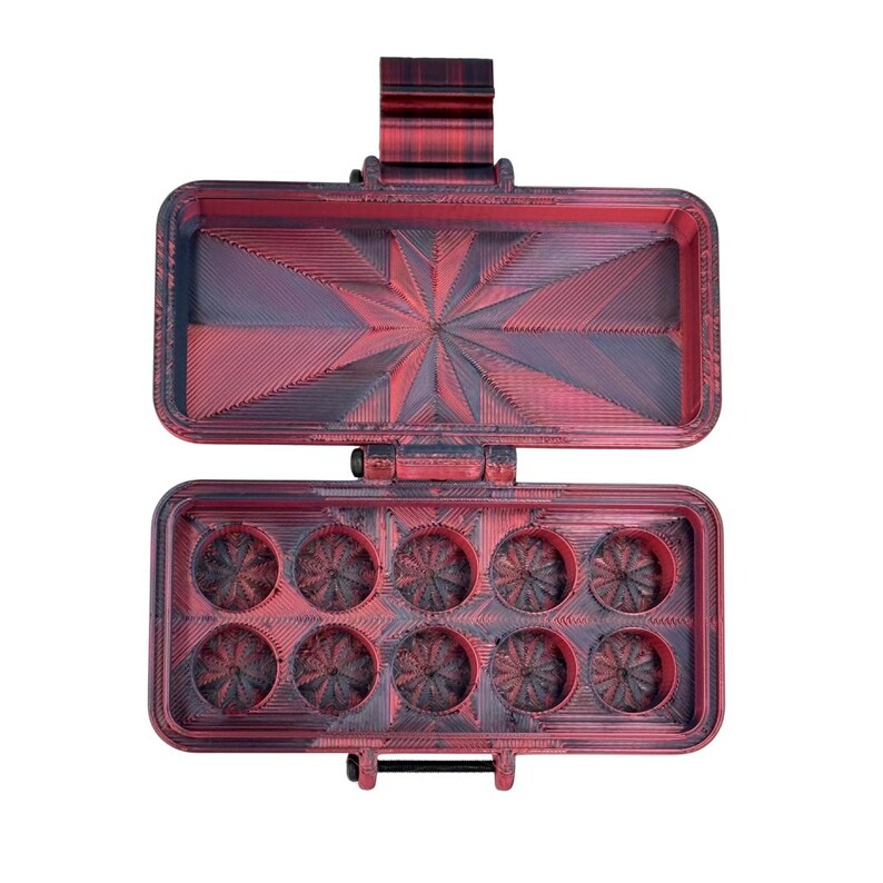 May include: A rectangular, hinged storage case with a red and black marbled finish. The interior lid features a starburst pattern, while the base contains ten circular compartments, each with a matching starburst design at the bottom.
