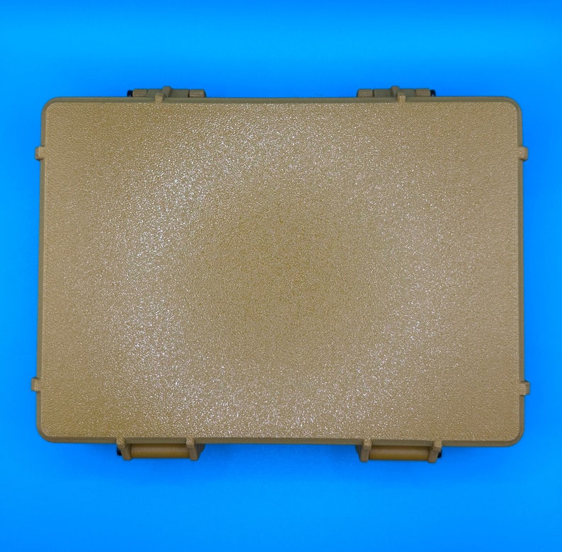 May include: A rectangular, tan-colored hard-shell protective case with a textured surface. The case features two prominent locking latches on the bottom edge and reinforced corners, providing a secure and durable storage solution.